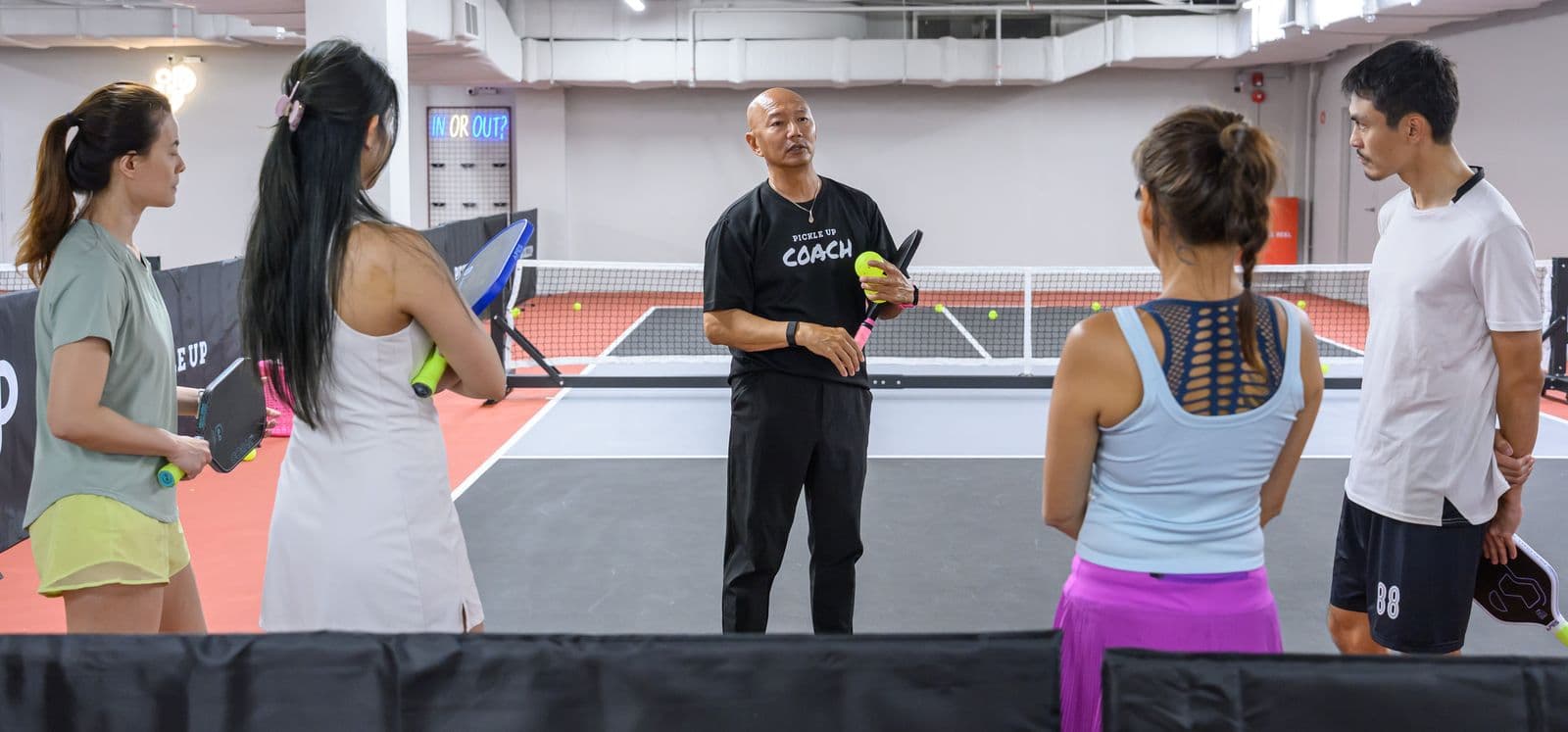 Coach Weber briefing a group class on court.