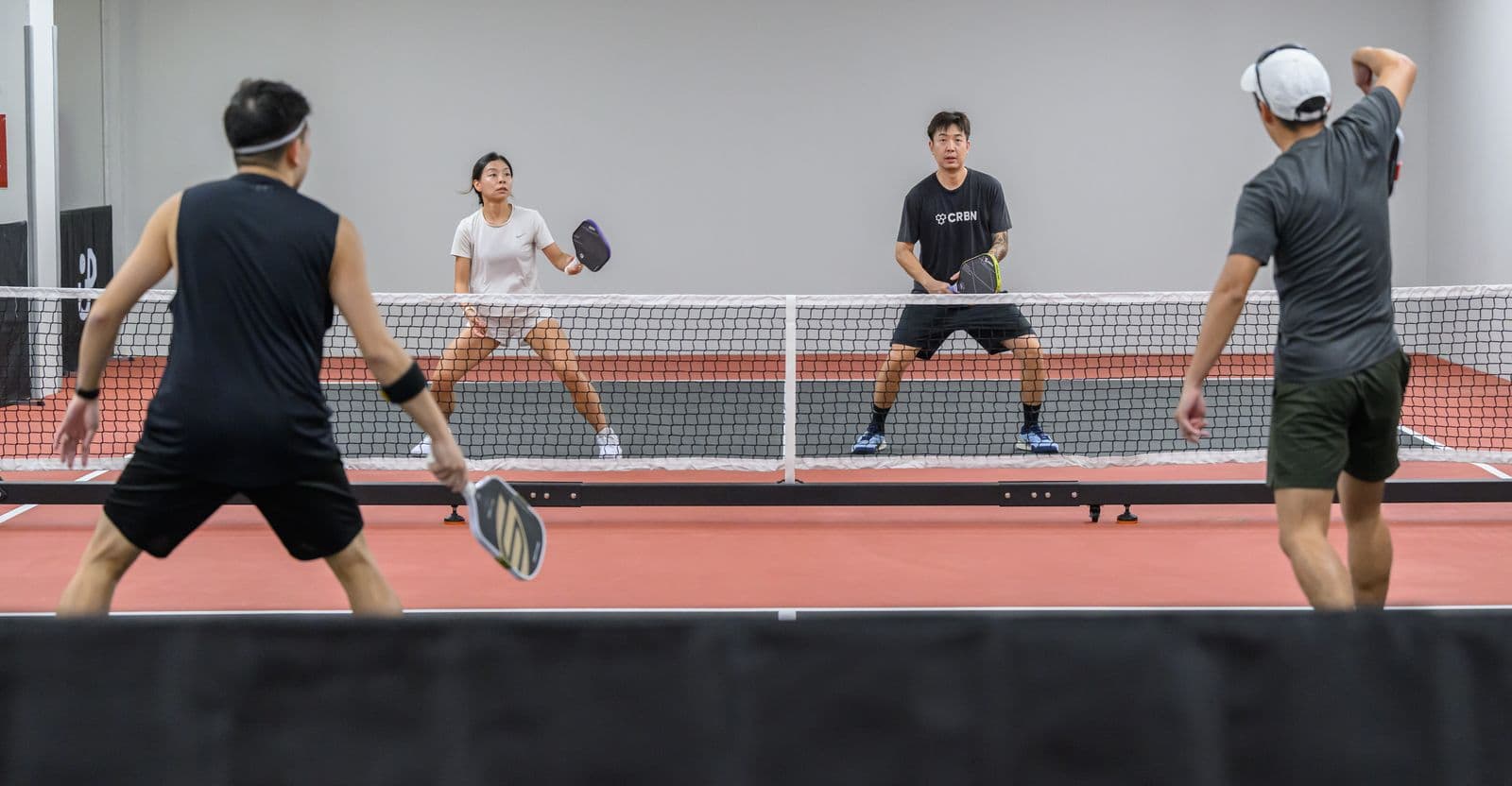 Four players at the net on a Signature court, a ball in the air.
