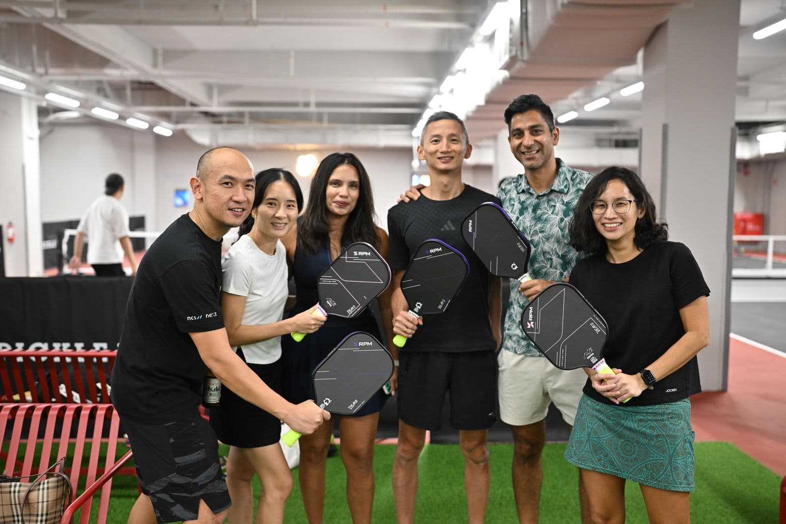 Six friends on the green turf, each holding an RPM paddle.
